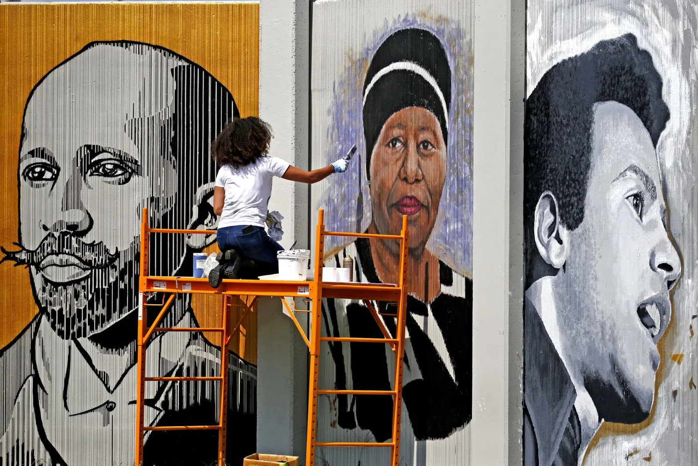 Artist Julia Bottoms-Douglas paints a portrait of Eva Doyle on “The Freedom Wall,” a public art project featuring portraits of local and national civil rights leaders